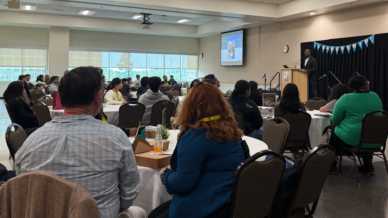 Audience seated at banquet tables listening to a keynote speaker during a leadership event