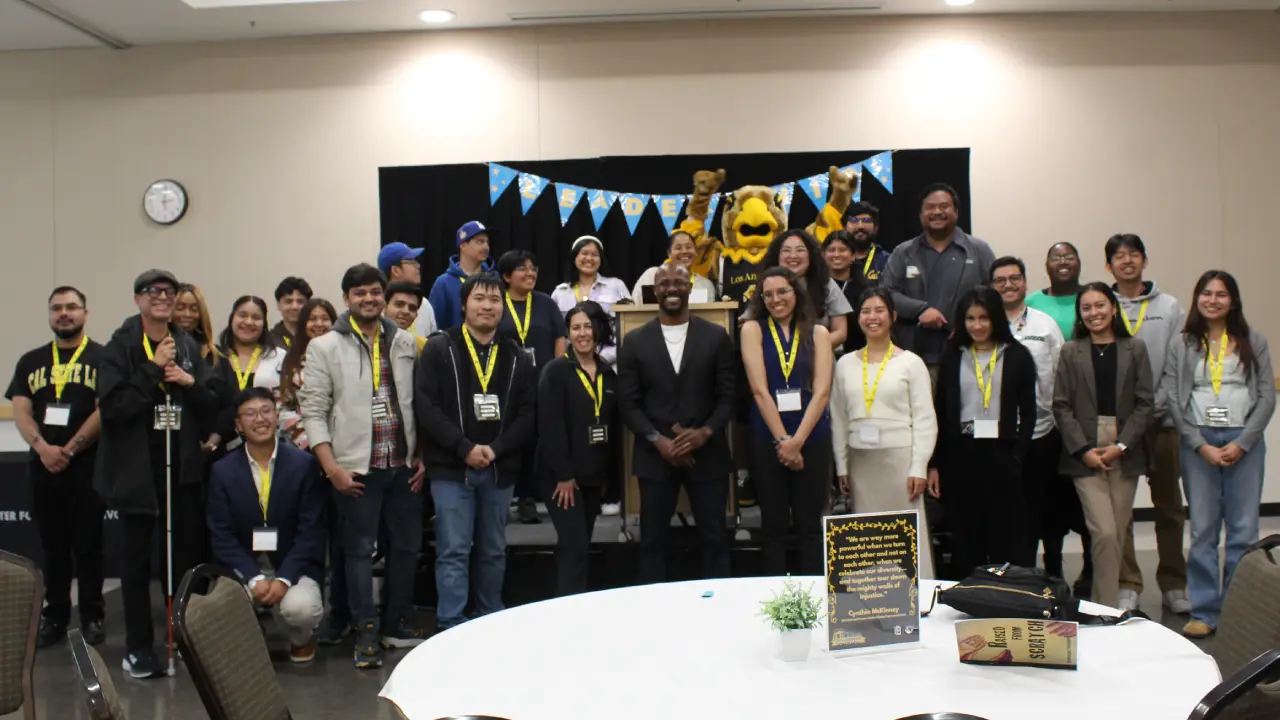 Group photo of students posing with Eddie the Golden Eagle mascot indoors